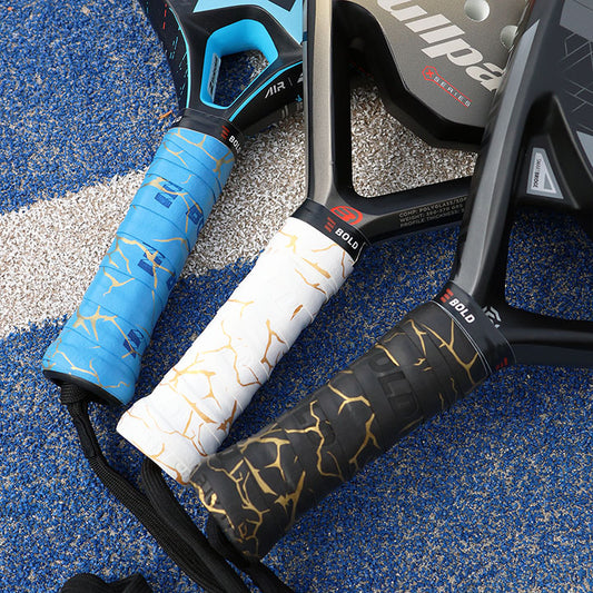 Three padel rackets with different handle grips on a textured surface